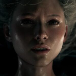 Obrazek pokazuje zbliżenie na twarz kobiety z jasnymi włosami, leżącej na plecach. Jej skóra jest wilgotna, a wyraz twarzy sugeruje niepokój lub zmartwienie.