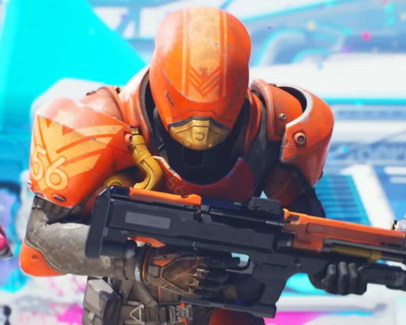 Postać w pomarańczowym pancerzu bojowym z numerem 56 na ramieniu celuje z futurystycznej broni w dynamicznej scenie z gry Splitgate 2. Tło jest rozmyte, wypełnione neonowymi kolorami i nowoczesną architekturą, co podkreśla sci-fi estetykę gry.