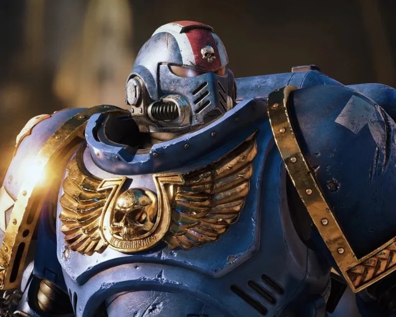 Space Marine z gry Warhammer 40,000: Space Marine 2 – postać w niebieskiej zbroi Ultramarines z detalami w złocie i charakterystycznym hełmem bojowym.