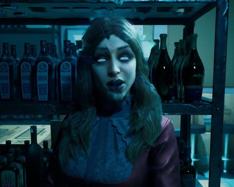 grafika promująca grę Vampire: The Masquerade – Bloodlines 2, przedstawia kobietę o długich jasnych włosach i jasnobłękitnych oczach, patrzy się prosto w kamerę a obraz jest nieco zniekształcony, jakby przez filtr rozbitego lustra, za nią w tle widać metalowy regał ze szklanymi butelkami