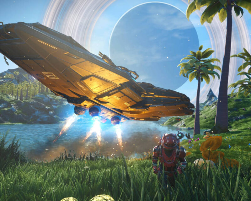 To zdjęcie przedstawia scenę z gry wideo No Man's Sky. Na pierwszym planie, w trawiastym terenie, stoi postać gracza w skafandrze kosmicznym. Patrzy ona w kierunku dużego statku kosmicznego, który właśnie wylądował na brzegu jeziora, otoczony palmami i egzotycznymi roślinami. Z silników statku wylatują strumienie niebieskiego światła. W tle widać dużą, błękitną planetę z pierścieniami, a na niebie znajdują się chmury. Scena jest bardzo kolorowa i nasycona, typowa dla estetyki tej gry, która łączy eksplorację, przetrwanie i kosmiczne podróże.