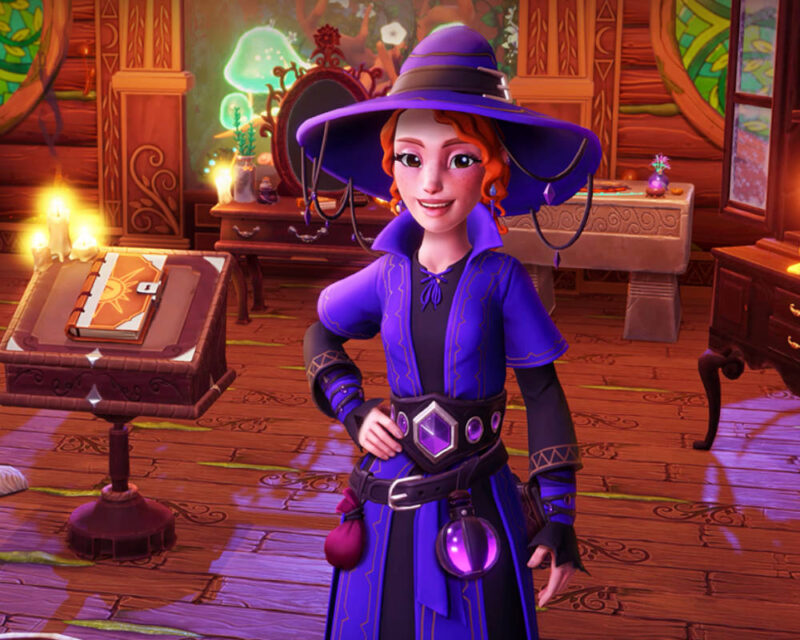 Na obrazku widać postać gracza (awatara) z gry Disney Dreamlight Valley, ubraną w fioletowy strój wiedźmy lub czarodziejki, co sugeruje tematykę Star Path "Witchful Thinking". Postać stoi w jasnym, drewnianym pomieszczeniu, które przypomina przytulną pracownię lub magiczny pokój. Ma rude włosy i szeroki, fioletowy kapelusz z lekko opuszczonym rondem. Jej strój to długa, fioletowa tunika lub płaszcz z ciemnymi akcentami, ozdobiony heksagonalną, błyszczącą sprzączką w pasie, do którego doczepione są małe flakony z eliksirami. W tle widać meble, które pasują do magicznego wystroju: po lewej stronie znajduje się drewniana ambona z otwartą księgą z symbolami słońca, oświetlona płonącymi świecami, a dalej stoi toaletka z ozdobnym lustrem i flakonami oraz zielonym, świecącym grzybem na półce. Cała scena jest ciepło oświetlona, co podkreśla magiczną i tajemniczą atmosferę.