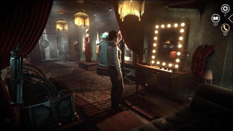 Kobieta stoi przed lustrem z lampkami. W tle widać długie suknie na manekinach, na ziemi tureckie dywany, przy syficie wiszą ozdobne lampy, dające ciepłe świało.