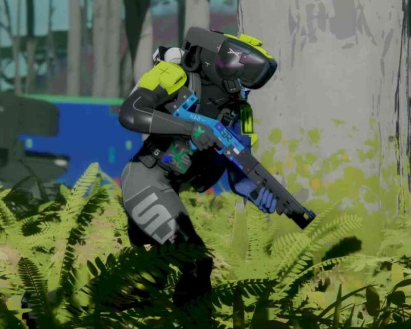 Postać w futurystycznym pancerzu bojowym, z czarnym hełmem i przyciemnianą wizjerą, porusza się w pozycji skradania wśród zielonej roślinności. Trzyma karabin z niebiesko-czarną kolbą, opierając się o betonową ścianę pokrytą śladami farby i graffiti. W tle widoczne są industrialne elementy konstrukcji. Grafika z gry Marathon.