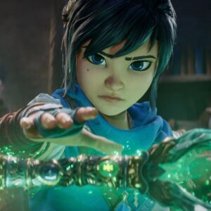 Zrzut ekranu z zapowiedzi gry Kena: Scars of Kosmora. Prezentuje tytułową bohaterkę – czarnowłosą i niebieskooką Przewodniczkę Dusz w biało-niebieskich szatach – z dłonią wyciągniętą nad swojego rodzaju magicznym artefaktem, emitujacym zielonkawą poświatę. W tle biblioteczka oraz dwóch innych bohaterów. Grafika utrzymana w bajkowym stylu.