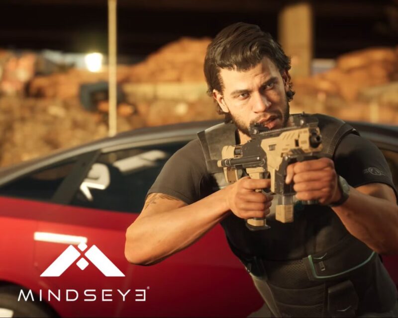 Mężczyzna w czarnej koszulce i kamizelce taktycznej celuje z broni palnej, stojąc obok czerwonego samochodu. W tle widać rozmyte, pustynne otoczenie i zabudowania. W lewym dolnym rogu znajduje się logo z napisem ‘Mindseye’.