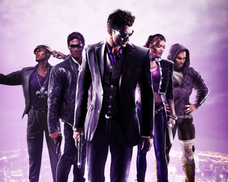 Grafika promocyjna gry Saints Row przedstawiająca pięcioosobową grupę bohaterów stojących nocą na tle oświetlonego miasta. Centralna postać w czarnym garniturze i okularach trzyma broń, pozostałe osoby w fioletowo-czarnych strojach również są uzbrojone. Całość utrzymana w purpurowej kolorystyce, z mrocznym, gangsterskim klimatem.