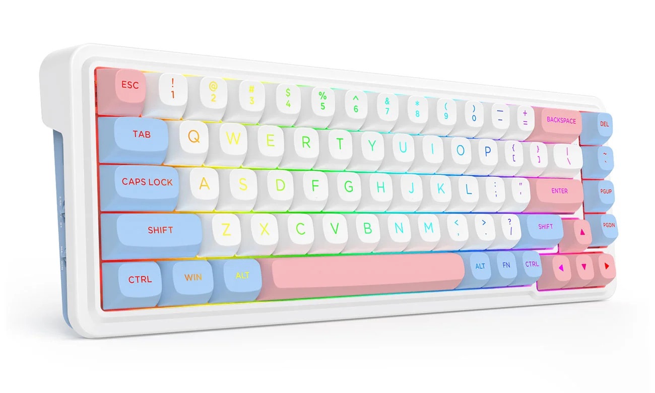 Zdjęcie prezentuje bezprzewodową klawiaturę mechaniczną o ultrakompaktowym układzie 65%, która przyciąga wzrok radosną, pastelową kolorystyką i nowoczesnym designem. Urządzenie posiada białą, grubą obudowę z zaokrąglonymi rogami, w której osadzono klawisze w trzech uzupełniających się kolorach: klasycznej bieli dla głównej sekcji liter, delikatnym błękicie dla klawiszy modyfikatorów oraz stonowanym różu dla przycisków funkcyjnych, takich jak Esc, Enter czy Spacja. Pod przezroczystymi oznaczeniami klawiszy widoczne jest intensywne, wielokolorowe podświetlenie RGB, które tworzy płynne przejścia tonalne na całej powierzchni panelu. Mimo niewielkich rozmiarów, klawiatura zachowuje dedykowane strzałki oraz pionową kolumnę przycisków nawigacyjnych po prawej stronie, a na jej lewym boku dostrzec można przełączniki trybów łączności, co podkreśla jej funkcjonalność i mobilny charakter.