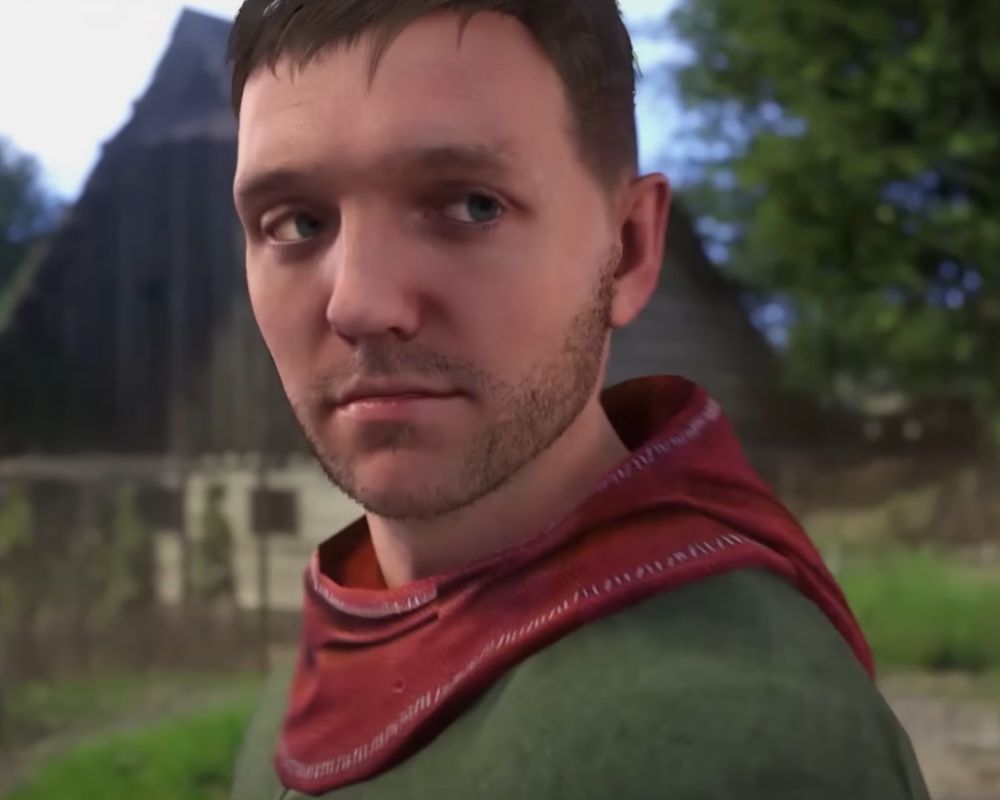Ujęcie z gry Kingdom Come: Deliverance, ukazujące Henryka ze Skalicy przed kuźnią Marcina. To moment jeszcze przed rozpoczęciem przygody. Henryk ubrany jest w zieloną koszulę i czerwony kaptur.
