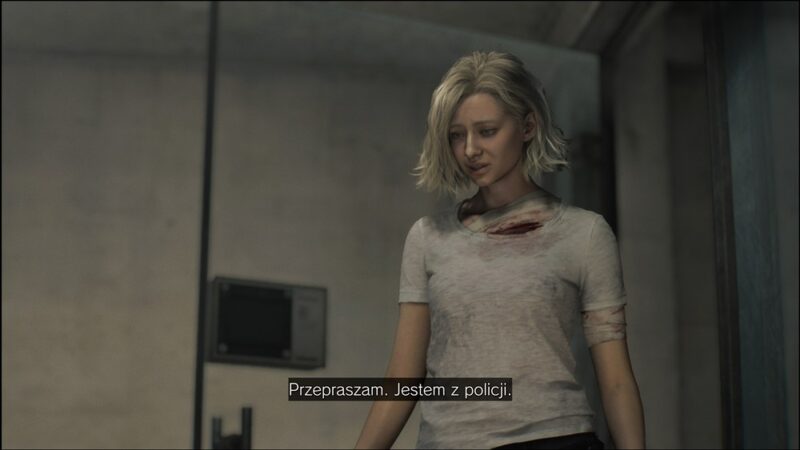 Szczupła blondwłosa dziewczyna w szarej koszulce, spod koszulki wysuwa się zakrawiony bandaż na klatce piersiowej i ramieniu. Mówi: "Przepraszam. Jestem z policji".