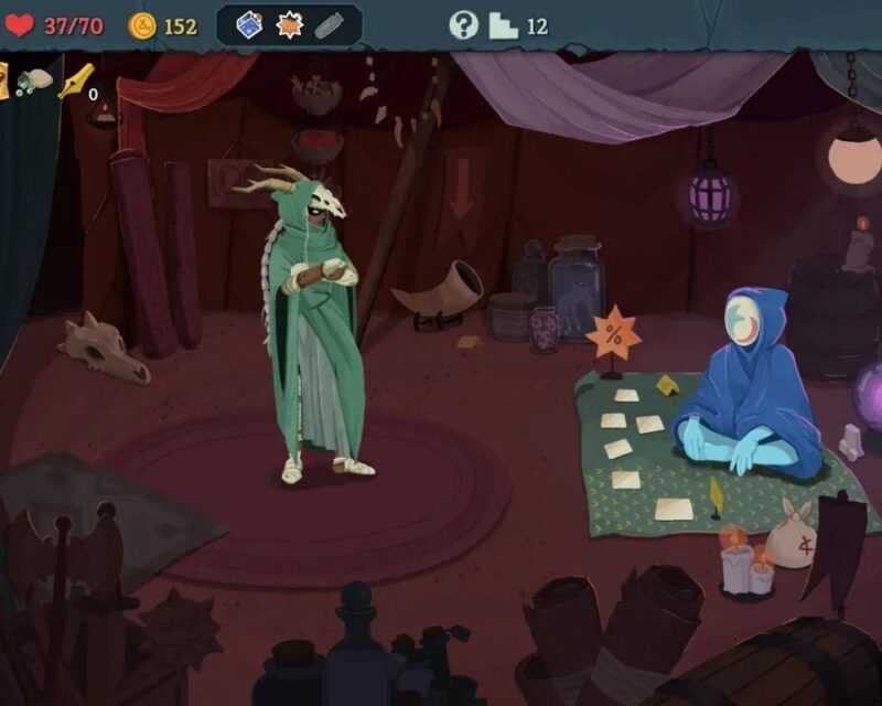 Na zdjęciu widać kadr z gry Slay the Spire 2 przedstawiający ekran handlarza wewnątrz mrocznego namiotu. Po lewej stronie stoi postać w długiej, zielonej szacie z czaszką zamiast maski i rogami, natomiast po prawej siedzi kupiec w niebieskim kapturze z białą maską na twarzy. Postać siedzi na wzorzystym dywanie z rozłożonymi kartami, a wokół niej znajdują się zapalone świece i sakiewki ze złotem. W tle widać półki z miksturami i zwojami, a górna część ekranu zawiera interfejs z liczbą punktów życia (37/70) oraz złotem (152).