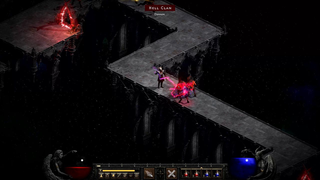 Scena walki z gry Diablo II: Resurrected pokazana w rzucie izometrycznym. Postać gracza stoi na wąskim, kamiennym moście zawieszonym w ciemnej, pustej przestrzeni i walczy z dwoma czerwonymi demonami. Bohater atakuje przeciwników magicznym uderzeniem, które świeci czerwonym światłem. Most jest częścią gotyckiej konstrukcji z kolumnami i łukami, a po lewej stronie na platformie widać czerwony, świecący portal. Na dole ekranu znajduje się interfejs gry z paskiem umiejętności, ikonami zdolności oraz kulami życia i many.