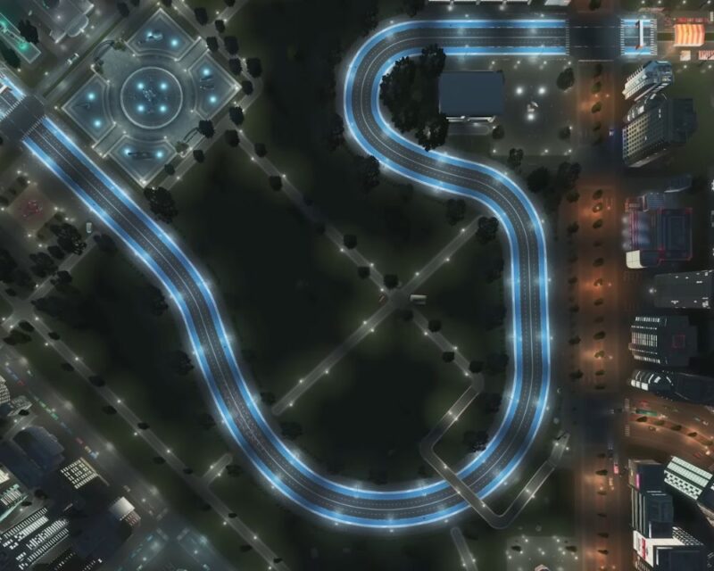 Zrzut ekranu z gry Cities: Skylines. Obrazek prezentuje nowy typ drogi, jaki będzie dostępny w grze po zainstalowaniu DLC Race Day, który wychodzi 10 marca 2026 roku. To szeroka, czteropasmowa aleja ze specjalną strefą na krawędziach, przeznaczoną dla widzów. Została ona wkomponowana w miejski, nocny krajobraz.