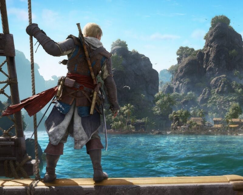 Edward Kenway stoi na krawędzi pokładu statku, jedną ręką trzymając się liny. Ma na sobie charakterystyczny strój asasyna: długi, jasny płaszcz z kapturem, skórzane pasy z przypiętą bronią, czerwony pas w talii oraz wysokie, skórzane buty. Na plecach widoczna jest broń, a u pasa zwisają pistolety i szabla. Spogląda w stronę tropikalnej wyspy z wysokimi, porośniętymi roślinnością klifami, turkusową wodą oraz niewielką nadmorską osadą z drewnianymi budynkami i palmami.