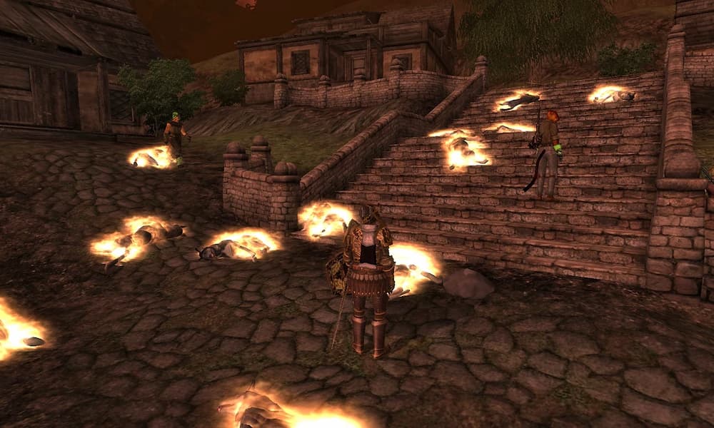 „Zrzut ekranu z gry fantasy przedstawiający kamienną ulicę i szerokie schody prowadzące między budynkami o drewniano‑kamiennej architekturze. W kilku miejscach stoją opancerzone postacie — jedna na pierwszym planie, kolejne na schodach i w głębi alejki. Na bruku i stopniach leżą liczne ciała lub sylwetki otoczone intensywną, jasną poświatą przypominającą magiczny ogień lub energię. Niebo ma czerwony odcień, co potęguje dramatyczny, bitewny nastrój sceny.