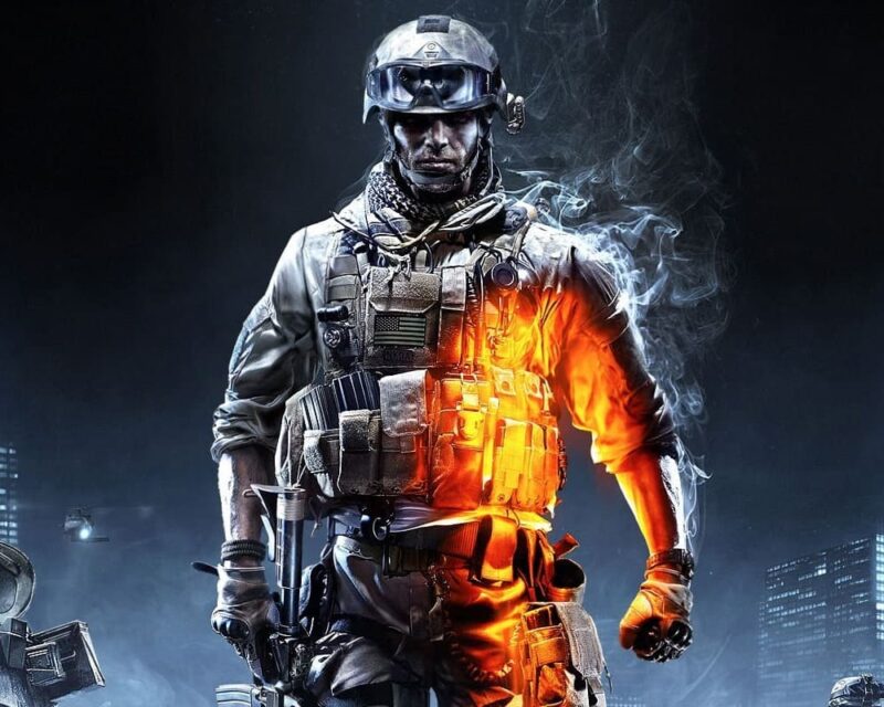 obraz przedstawia postać żołnierza, który stanowi centralny punkt kompozycji, nawiązując do stylistyki znanej z serii gier wideo Battlefield. Mężczyzna jest w pełnym rynsztunku bojowym, mając na sobie hełm z goglami, kamizelkę taktyczną z licznymi ładownicami oraz chustę typu arafatka wokół szyi. Najbardziej charakterystycznym elementem grafiki jest dynamiczny kontrast świetlny: prawa strona postaci płonie intensywnym, pomarańczowym blaskiem ognia i iskier, podczas gdy lewa strona oraz tło utrzymane są w chłodnej, mrocznej, niebiesko-czarnej tonacji. Wokół żołnierza unoszą się kłęby gęstego dymu, a w oddali majaczą zarysy miejskiej zabudowy oraz śmigłowca, co podkreśla atmosferę intensywnego konfliktu zbrojnego i wysokiego napięcia