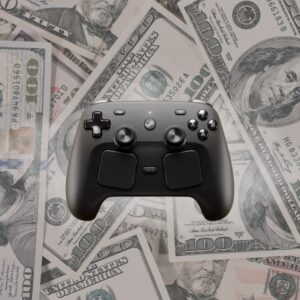 Czarny kontroler Valve Steam Controller na tle rozrzuconych banknotów 100 dolarów amerykańskich. Grafika sugeruje wysoką cenę Steam Controller