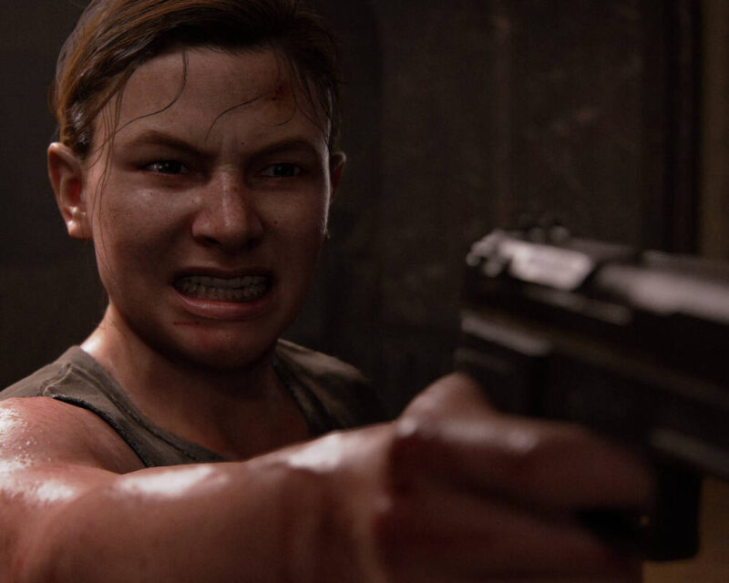 Obrazek to dramatyczny, bliski portret kobiety o intensywnym, gniewnym wyrazie twarzy, która patrzy prosto w obiektyw, trzymając w kierunku widza czarny pistolet. Kobieta, z wyraźnie widoczną muskulaturą ramion i spoconą skórą, ma spięte włosy i jest ubrana w szarą, zużytą koszulkę na ramiączkach. Jej twarz jest zniekształcona grymasem wściekłości: brwi są mocno ściągnięte, nos zmarszczony, a usta rozchylone, odsłaniając zęby w okrzyku lub syknięciu, z kropelką krwi na wardze. Pistolet jest trzymany obiema rękami w mocnym, wyciągniętym chwycie, z wyraźnie widocznymi detalami zamka i lufy, choć tylna część pistoletu jest lekko rozmyta. Oświetlenie jest słabe, tworząc cienie, które podkreślają wyraz jej twarzy i teksturę skóry. Tło jest ciemne i niewyraźne, sugerując zamkniętą, być może brudną przestrzeń, jak piwnica lub korytarz, co wzmacnia poczucie klaustrofobii i zagrożenia. Obraz jest wykonany w fotorealistycznym stylu, z dużą dbałością o detale skóry, włosów i materiału broni.