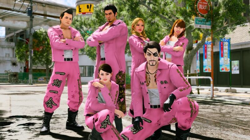 Grupa siedmiu postaci stoi na ulicy w miejskim otoczeniu, prawdopodobnie w Japonii. Wszyscy ubrani są w dopasowane, jaskrawo różowe stroje przypominające uniformy gangów, ozdobione czarnymi wzorami i napisami. Część osób stoi z założonymi rękami, inne kucają na pierwszym planie, patrząc pewnie w stronę widza. W tle widoczne są drzewa, znaki drogowe i zabudowa miejska. Cała scena ma styl realistycznej grafiki z gry wideo.