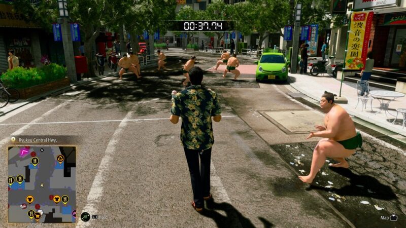 Scena z gry wideo, gdzie mężczyzna w hawajskiej koszuli idzie ostrożnie środkiem jezdni, a dookoła chodzą wojownicy sumo chcący go przewrócić.