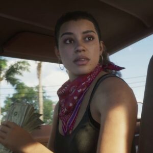 Lucia z GTA 6 siedzi we wnętrzu samochodu i trzyma w lewej dłoni gruby plik dolarów. Bohaterka ma ciemne włosy związane z tyłu, duże kolczyki koła oraz czerwoną bandanę zawiązaną na szyi. Ubrana jest w czarny top, a jej twarz oświetla ciepłe światło wpadające przez okno auta. Lucia spogląda nerwowo za siebie, jakby reagowała na coś dziejącego się poza kadrem. W tle widoczne są palmy, przewody elektryczne i słoneczne niebo.