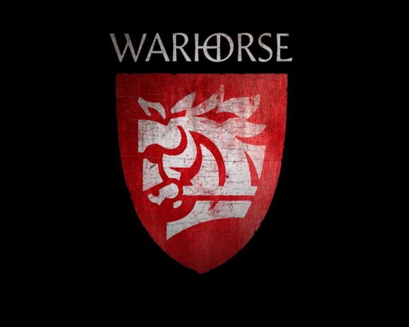 Logo studia Warhorse Studios na czarnym tle. Powyżej czerwonej tarczy widnieje stylizowany, szary napis „WARHORSE” z wpisanym w literę „O” symbolem krzyża w okręgu. Poniżej znajduje się pionowa, lekko nadszarpnięta tarcza rycerska w kolorze czerwonym z białym, minimalistycznym godłem przedstawiającym profil łba konia bojowego w stylizacji heraldycznej.