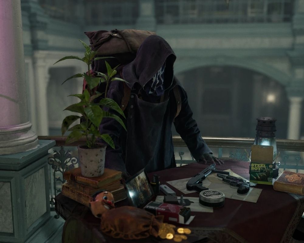 Handlarz z Resident Evil 4, ubrany w ciemny kaptur zasłaniający twarz i długi płaszcz, stoi pochylony nad stołem zastawionym ekwipunkiem. Na blacie widać kilka pistoletów, pudełka z amunicją, rozsypane monety oraz drobne przedmioty, a obok leżą książki i niewielka lampa rzucająca przytłumione światło.