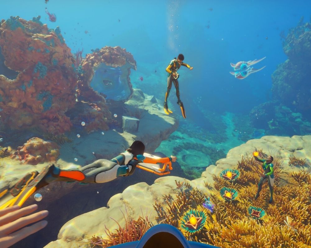 Grafika z Subnautica 2 przedstawiająca grupę nurków eksplorujących kolorowe głębiny oceanu obcej planety, pełne raf koralowych, skalnych formacji i tajemniczych morskich stworzeń.