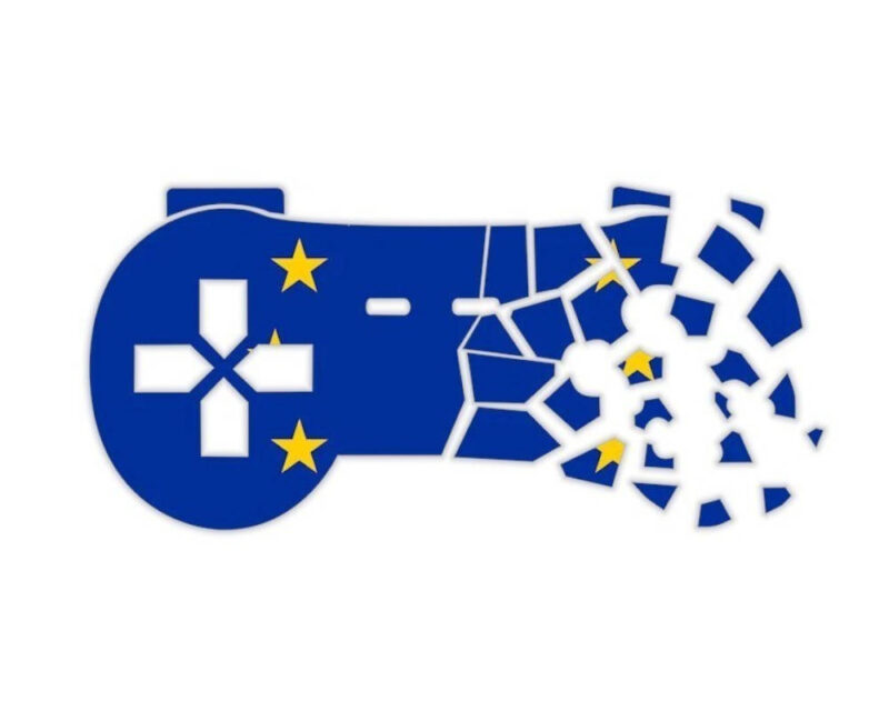 Grafika przedstawia sylwetkę kontrolera do gier na jednolitym, białym tle, która została pokryta motywem flagi Unii Europejskiej – intensywnym niebieskim kolorem oraz charakterystycznymi, żółtymi gwiazdami. Po lewej stronie pada wyraźnie widać biały krzyżak (D-pad) oraz dwie gwiazdy ulokowane nad nim i pod nim, podczas gdy na środku znajdują się dwa podłużne przyciski funkcyjne. Prawa strona kontrolera ulega całkowitej destrukcji, pękając i rozpadając się na dziesiątki drobnych, oderwanych od siebie fragmentów, wśród których można dostrzec pozostałe żółte gwiazdy z unijnego symbolu. Taka kompozycja tworzy wymowną, symboliczną ilustrację rozpadu, niszczenia lub kryzysu związanego z rynkiem gier wideo w kontekście europejskich regulacji prawnych.